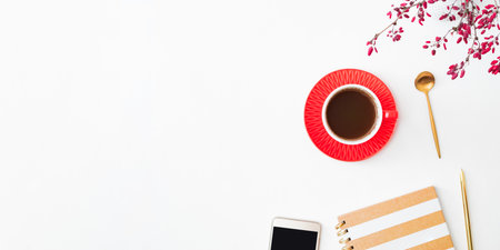 Flat lay composition with cup of coffee, branches with red berries and notebook on a white backgroundの写真素材
