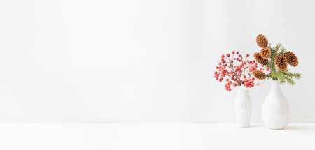Home interior decor elements. Small red apples in a vase and branches of spruce with cones on a light backgroundの写真素材