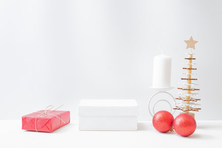 Empty white box and wooden christmas tree, gift box, red balls on a light background. Mockup banner, podium for display of advertise productの写真素材