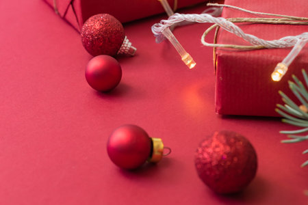 Frame with fir branches, christmas balls and gift box on a red background