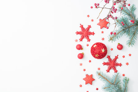Flat lay christmas frame with red berries, fir branches, snowflakes and red balls on a white background. Merry christmas card and copy space for your textの写真素材