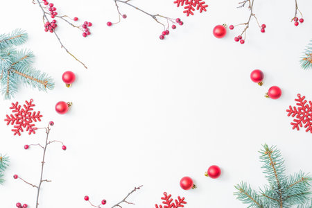 Flat lay christmas frame with red berries, fir branches, snowflakes and red balls on a white background. Merry christmas card and copy space for your textの写真素材