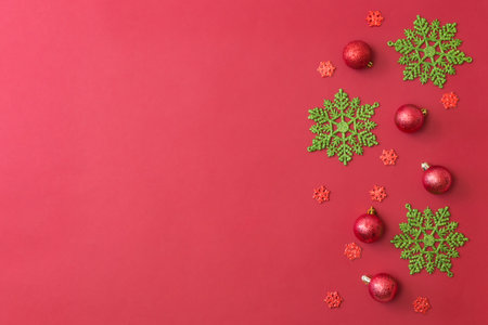 Flat lay border with christmas balls and snowflakes on a red backgroundの写真素材