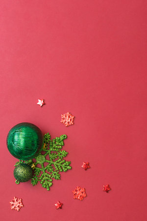 Flat lay frame with christmas balls and snowflakes on a red backgroundの写真素材