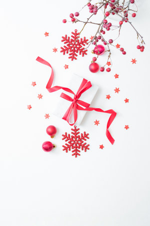 Flat lay frame with red berries, christmas red balls and gift box on a white background. Merry christmas card and copy space for your textの写真素材