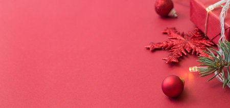Frame with fir branches, christmas balls and gift box on a red backgroundの写真素材