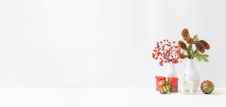Home interior decor elements. Small red apples in a vase and branches of spruce with cones on a light backgroundの写真素材