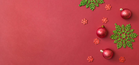Flat lay border with christmas balls and snowflakes on a red backgroundの写真素材