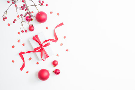Flat lay frame with red berries, christmas red balls and gift box on a white background. Merry christmas card and copy space for your textの写真素材