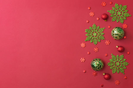 Flat lay border with christmas balls and snowflakes on a red backgroundの写真素材