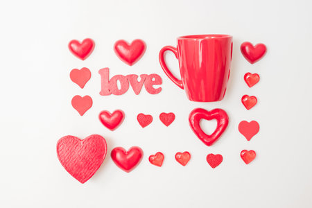 Flat lay valentines day pattern with red cup and red hearts on a white background. valentine's day greeting cardの写真素材