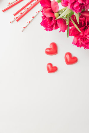 Flat lay valentines day frame with red peonies and red hearts on a white background. Valentines day banner with copy spaceの写真素材