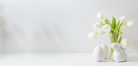 White spring tulips in a vase, easter eggs on a white table. Mock up for display worksの写真素材