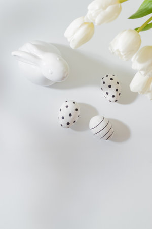 Flat lay easter composition with white tulips in a vase and easter eggs on a light backgroundの写真素材