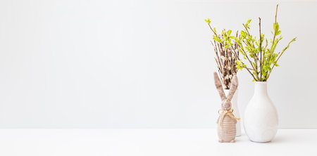 Willow branches in a vase and easter bunny on a light background. Easter background with copy space