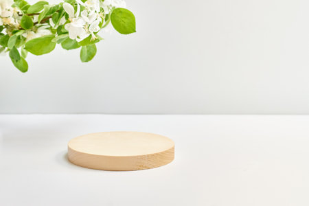 Empty round wooden podium for product presentation and spring flowers on a light background. Mockup concept with copy spaceの写真素材