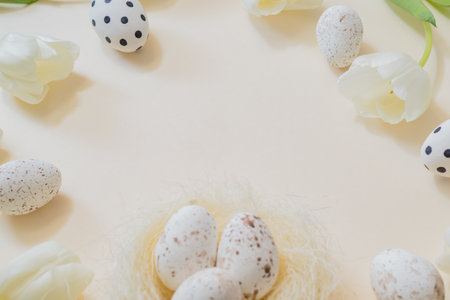 Easter composition with white tulips and easter eggs on a beige backgroundの写真素材