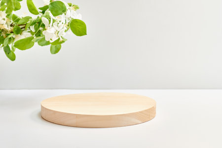 Empty round wooden podium for product presentation and spring flowers on a light background. Mock up for display worksの写真素材