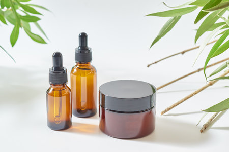 Brown glass bottles of cosmetics and jar on a light background. Concept organic natural cosmetic products for skincareの写真素材