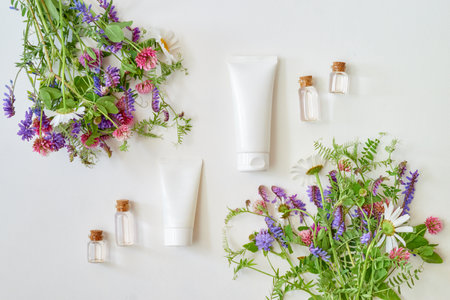 Cosmetic cream tubes packaging and wildflowers on white background. Natural skin care concept, mockup for designの写真素材