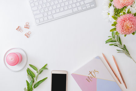 Flat lay home office desktop with smartphone, notebook, flowers in a vase, office supplies on a light background. Top view banner background with copy spaceの写真素材