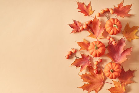 Flat lay frame with colorful autumn leaves and pumpkins on an orange backgroundの写真素材