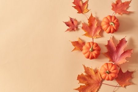 Flat lay frame with colorful autumn leaves and pumpkins on an orange backgroundの写真素材