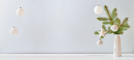 Christmas, New Year home decor. Empty white wall mock up with green fir branches in a vase on a white table. Mock up for display worksの写真素材
