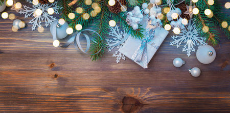 Flat lay christmas composition with fir branches and gift box, garland on a wooden table. Winter holiday background with copy spaceの写真素材