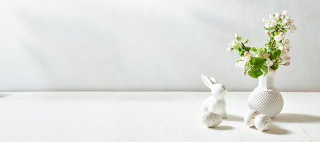 Spring flowers in a vase and easter eggs on a white table. Easter background with copy spaceの写真素材