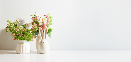 Spring flowers in a vase and easter bunny on a light background. Easter background with copy spaceの写真素材