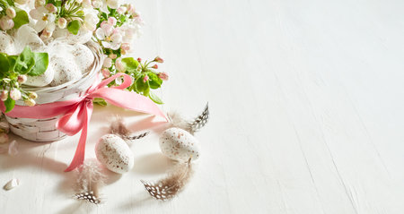 Holiday composition with spring flowers and easter eggs in basket on a light background. Happy easter concept with copy spaceの写真素材
