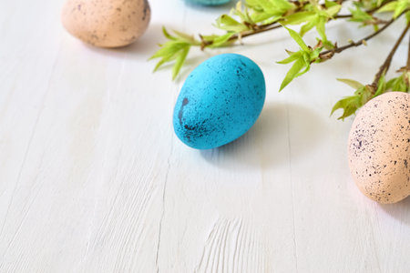 Branches with green leaves and easter eggs on a light background. Happy easter concept with copy spaceの写真素材