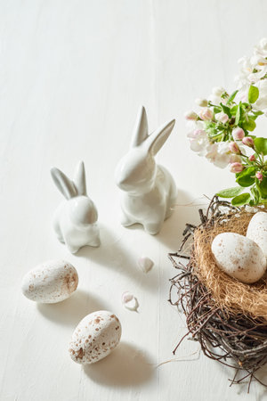 Holiday composition with spring flowers and easter eggs, white bunny on a light background. Happy easter concept with copy spaceの写真素材