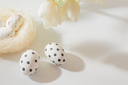 Easter composition with white tulips in a vase and easter eggs on a light backgroundの写真素材