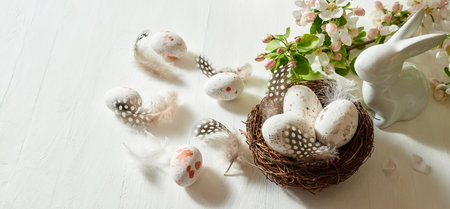 Holiday composition with spring flowers and easter eggs, white bunny on a light background. Happy easter concept with copy spaceの写真素材