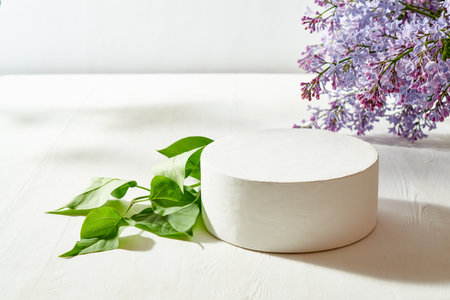 White round podium with lilac branches on a white tableの写真素材