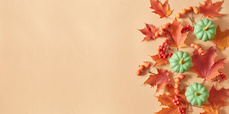 Flat lay frame with colorful autumn leaves and pumpkins on an orange backgroundの写真素材