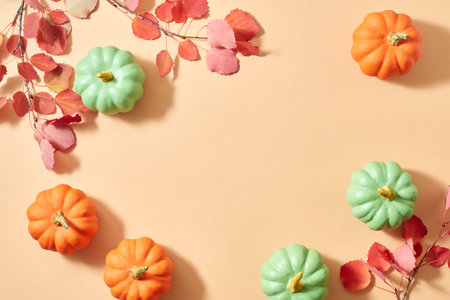 Flat lay frame with colorful autumn leaves and pumpkins on an orange backgroundの写真素材