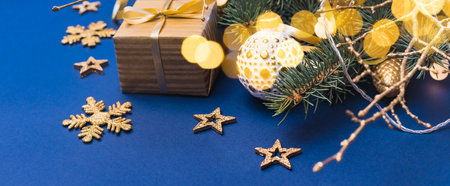 Christmas composition with fir branches and Christmas ball, garland, gift box on a blue background. Winter merry christmas holiday greeting cardの写真素材