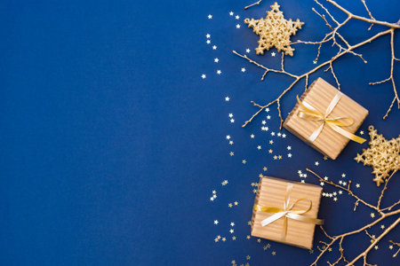 Flat lay christmas composition with golden gift box and christmas decorations, garland on a blue background. Winter holiday background with copy spaceの写真素材