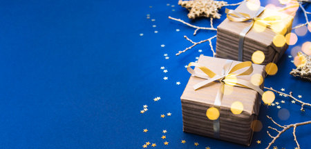 Christmas composition with golden gift box and Christmas decorations, garland on a blue background. Winter holiday background with copy spaceの写真素材