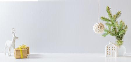 Christmas, New Year home decor. Empty white wall mock up with green fir branches in a vase, deer and gift box on a white table. Mock up for display worksの写真素材