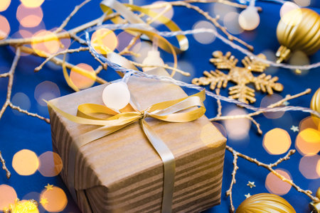 Christmas composition with golden gift box and Christmas decorations, garland on a blue background. Winter merry christmas holiday greeting cardの写真素材