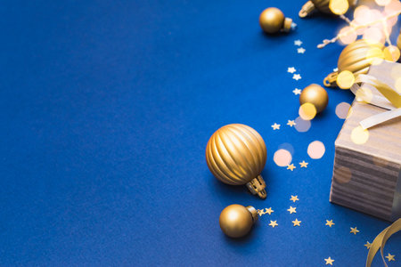 Christmas composition with golden gift box and Christmas decorations, garland on a blue background. Winter holiday background with copy spaceの写真素材