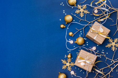 Flat lay christmas composition with golden gift box and christmas decorations, garland on a blue background. Winter holiday background with copy spaceの写真素材
