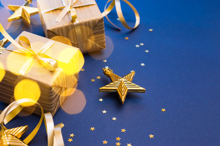 Christmas composition with golden gift box and Christmas decorations, garland on a blue background. Winter holiday background with copy spaceの写真素材