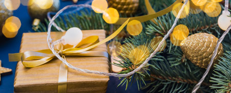 Christmas composition with fir branches and Christmas decorations, garland, gift box on a blue background. Winter merry christmas holiday greeting cardの写真素材