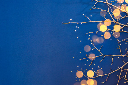 Flat lay christmas composition with golden branches and christmas decorations, garland on a blue background. Winter holiday background with copy spaceの写真素材