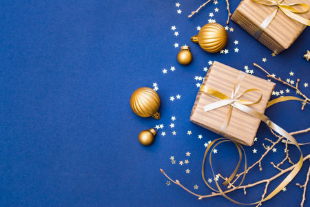 Flat lay christmas composition with golden gift box and christmas decorations, garland on a blue background. Winter holiday background with copy spaceの写真素材